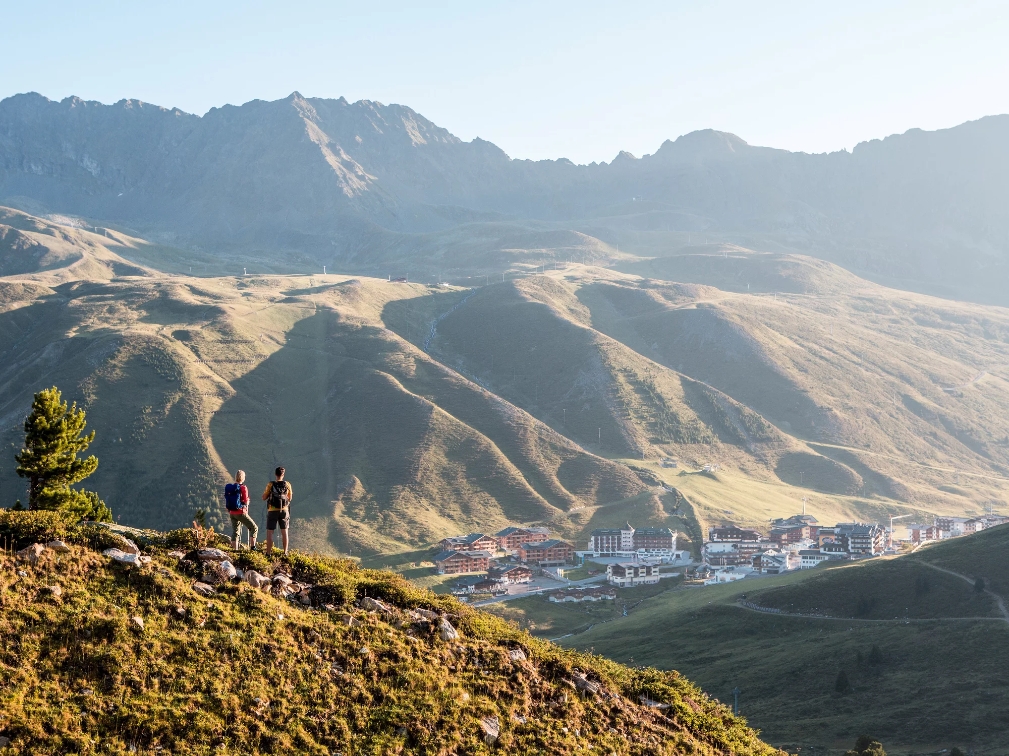 Zwei Wanderer schauen beim Bergpanorama ins Tal