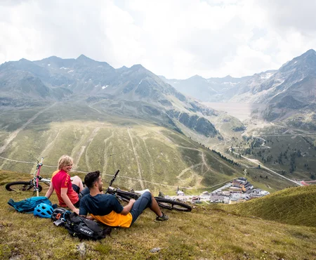 Zwei Biker machen eine Pause auf einer Bergwiese 