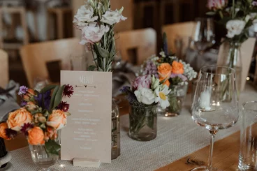 für eine Hochzeit gedeckter Tisch mit Blumen und Menükarte