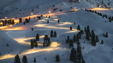 Luftaufnahme einer beleuchteten Rodelstrecke bei Sonnenuntergang