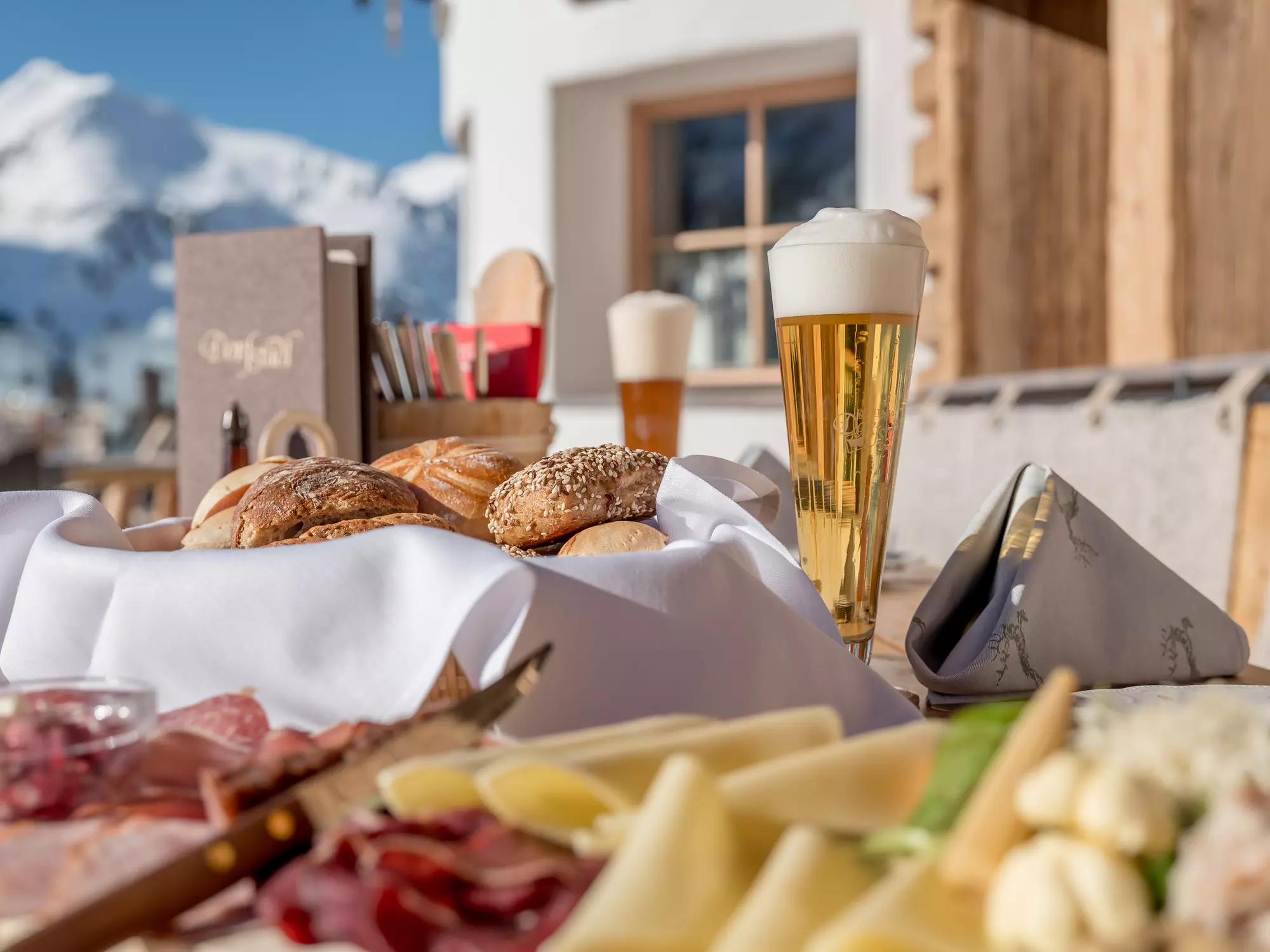 Brettljause mit Speck, Käse Brot und einem Bier auf einer Sonnenterrasse