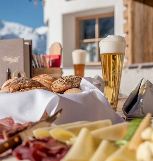 Brettljause mit Speck, Käse Brot und einem Bier auf einer Sonnenterrasse